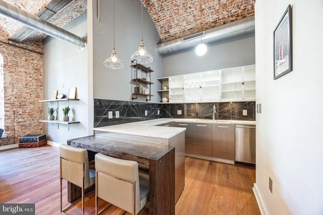 kitchen with a high ceiling, stainless steel dishwasher, pendant lighting, and tasteful backsplash