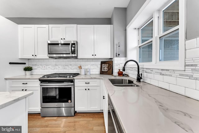 kitchen featuring white cabinets, sink, light wood-type flooring, and stainless steel appliances