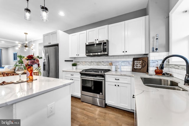 kitchen with white cabinetry, sink, light hardwood / wood-style floors, and appliances with stainless steel finishes