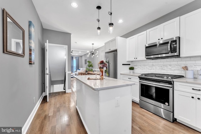 kitchen featuring white cabinetry, hanging light fixtures, a center island, and stainless steel appliances