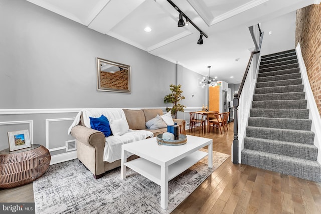 living room featuring a chandelier, wood-type flooring, and ornamental molding