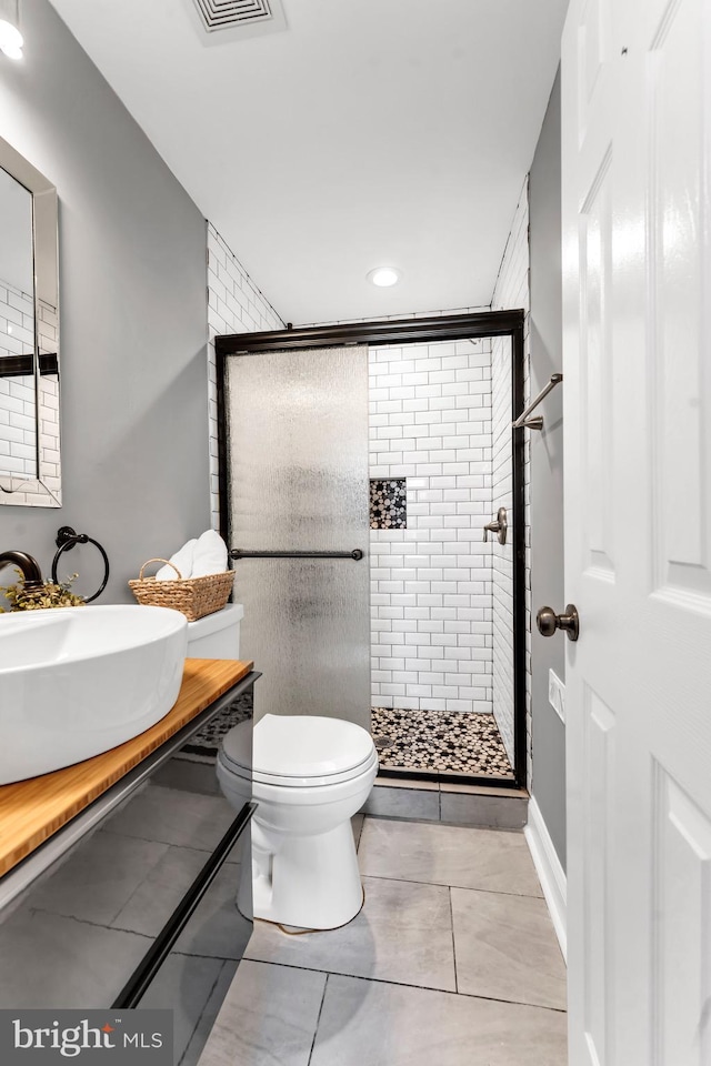 bathroom with toilet, sink, tile patterned flooring, and walk in shower