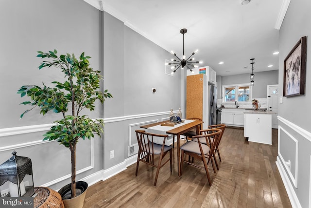 dining area with dark hardwood / wood-style flooring, an inviting chandelier, and crown molding