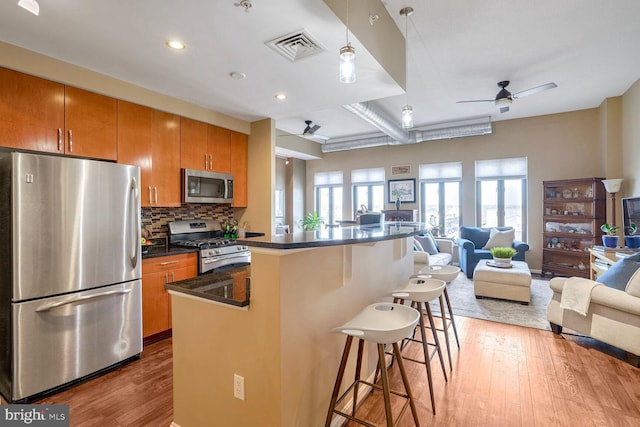 kitchen featuring ceiling fan, a center island, backsplash, a kitchen bar, and appliances with stainless steel finishes