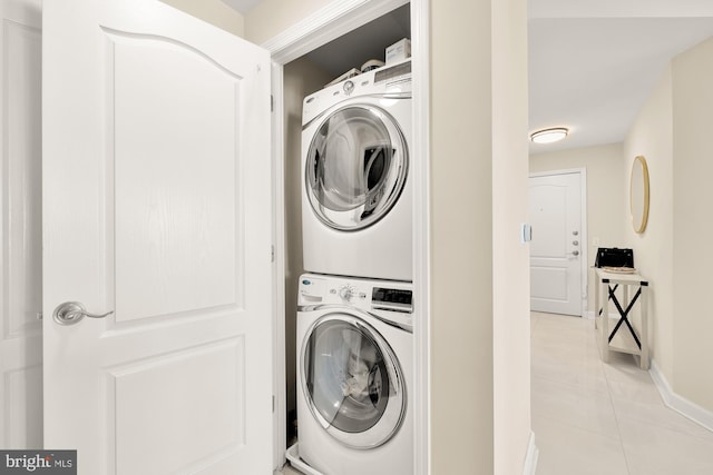 laundry room with light tile patterned floors and stacked washing maching and dryer