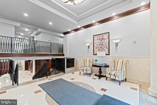 sitting room with a tray ceiling, light tile patterned floors, and ornamental molding