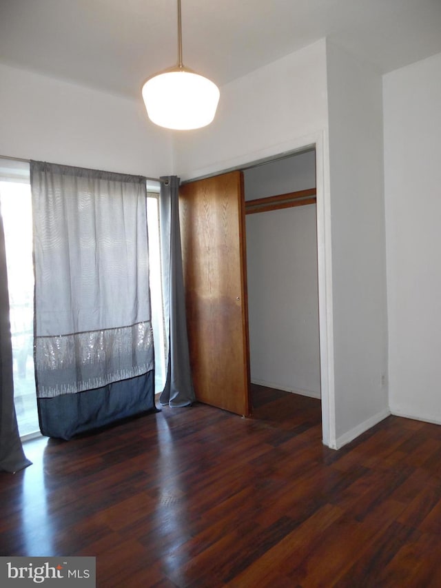 unfurnished bedroom featuring dark wood-type flooring and multiple windows