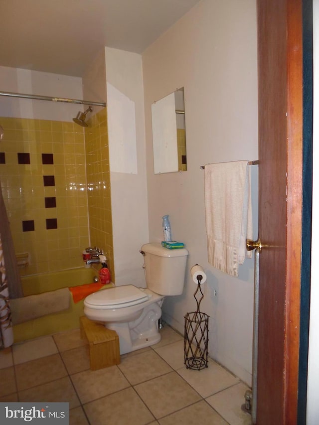 bathroom featuring tile patterned flooring, toilet, and tiled shower / bath