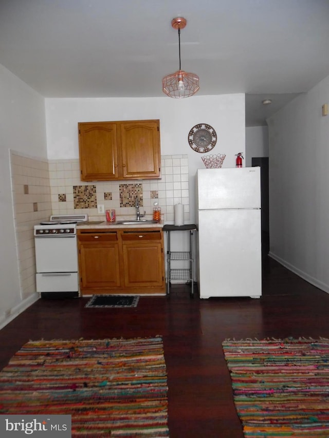 kitchen featuring stove, backsplash, white refrigerator, sink, and decorative light fixtures