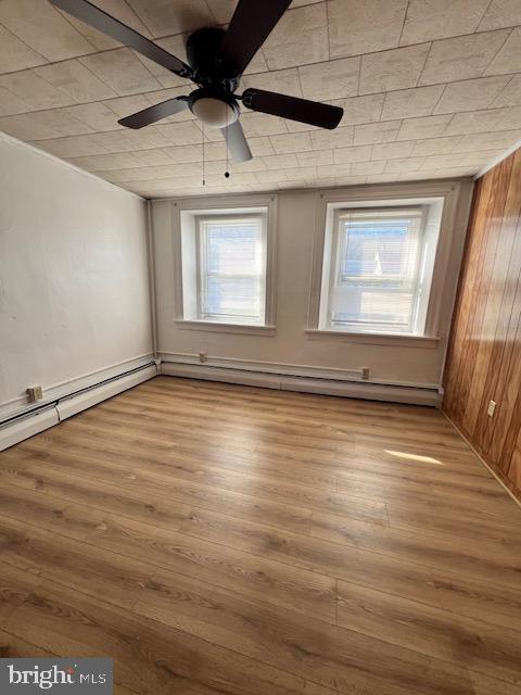 spare room featuring wooden walls, ceiling fan, and light hardwood / wood-style floors