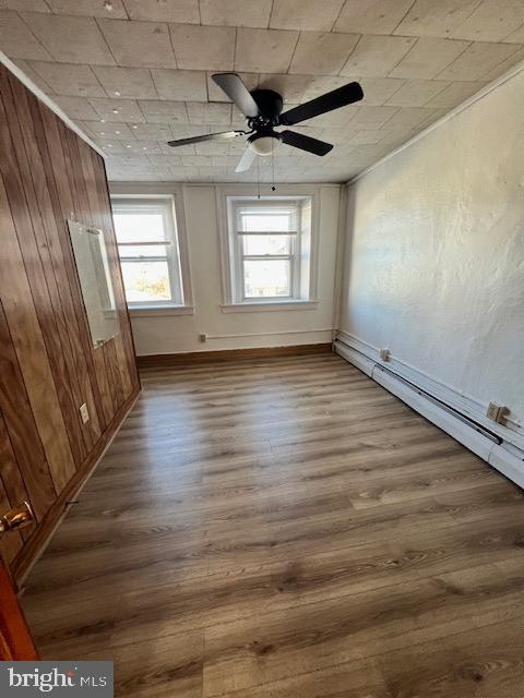 unfurnished room with ceiling fan, hardwood / wood-style floors, and wooden walls