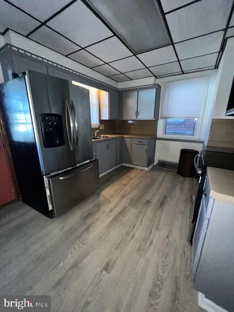 kitchen featuring fridge with ice dispenser, gray cabinets, light hardwood / wood-style floors, a paneled ceiling, and white stove