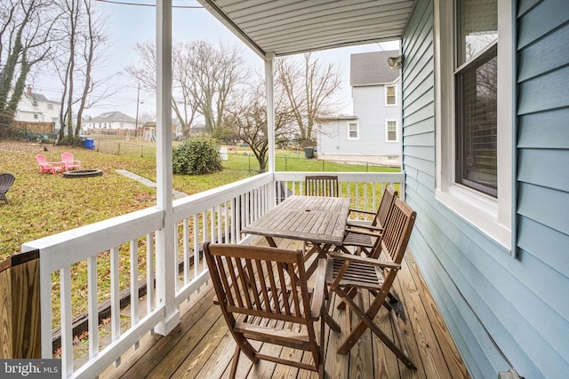 wooden terrace with a fire pit and a yard