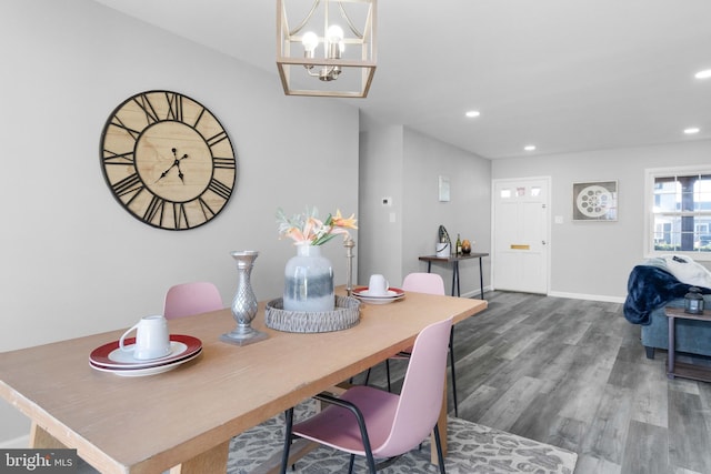 dining space with wood-type flooring and an inviting chandelier