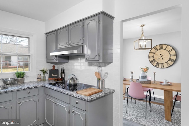 kitchen featuring gray cabinets, light stone countertops, black electric cooktop, tasteful backsplash, and wood-type flooring