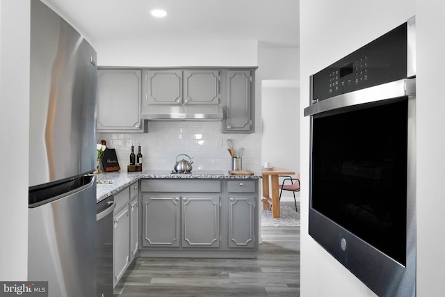 kitchen featuring tasteful backsplash, gray cabinetry, stainless steel appliances, and hardwood / wood-style flooring