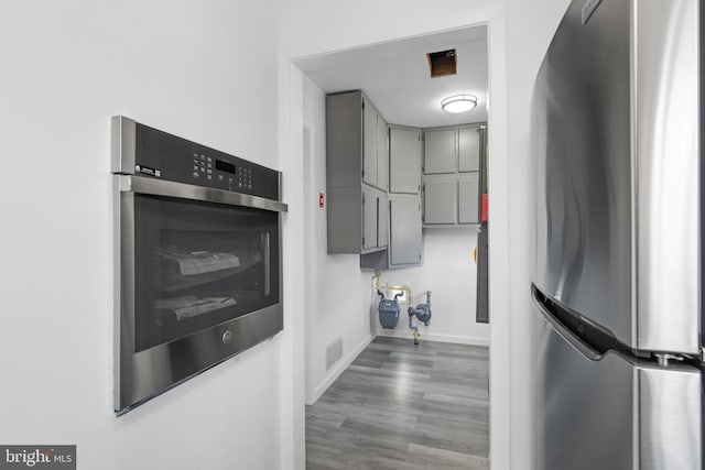 kitchen with gray cabinets, dark wood-type flooring, and stainless steel appliances