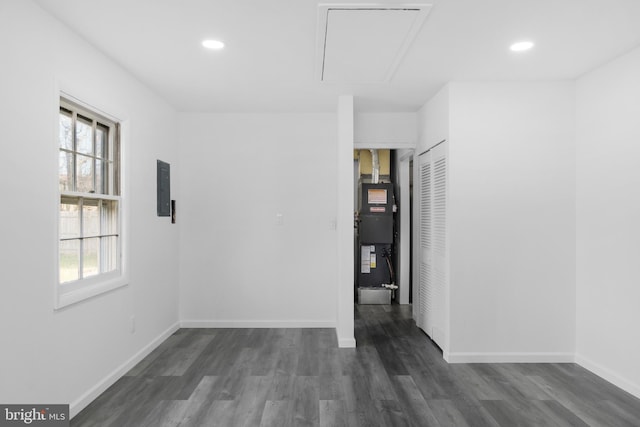 unfurnished room featuring electric panel, dark hardwood / wood-style flooring, and heating unit