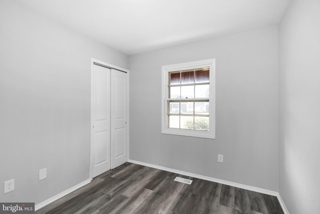 unfurnished bedroom featuring dark hardwood / wood-style floors and a closet