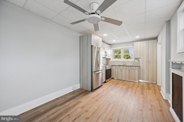 kitchen featuring a paneled ceiling, sink, ceiling fan, appliances with stainless steel finishes, and light hardwood / wood-style floors