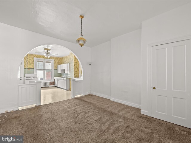 interior space with ceiling fan, radiator heating unit, and carpet