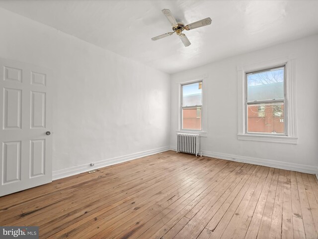 spare room with radiator heating unit, light hardwood / wood-style floors, and ceiling fan