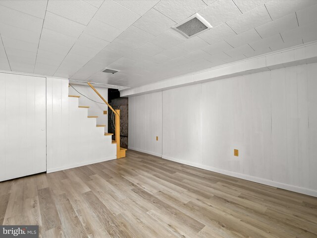 basement featuring wooden walls and hardwood / wood-style floors