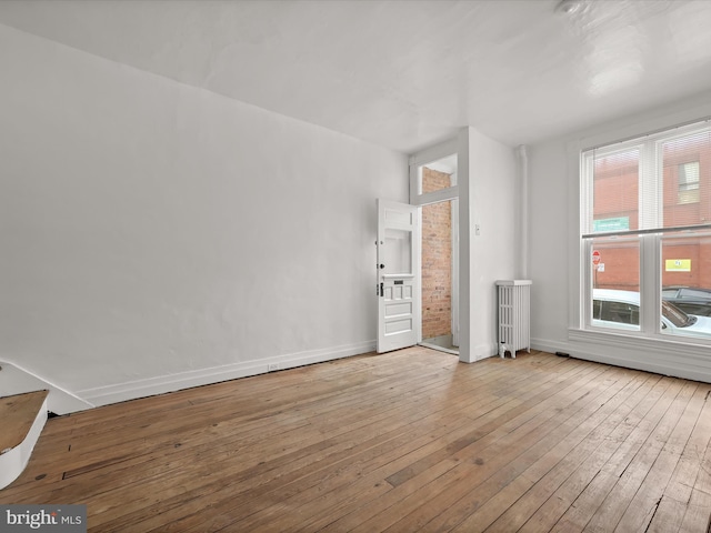 empty room with radiator heating unit and light hardwood / wood-style flooring