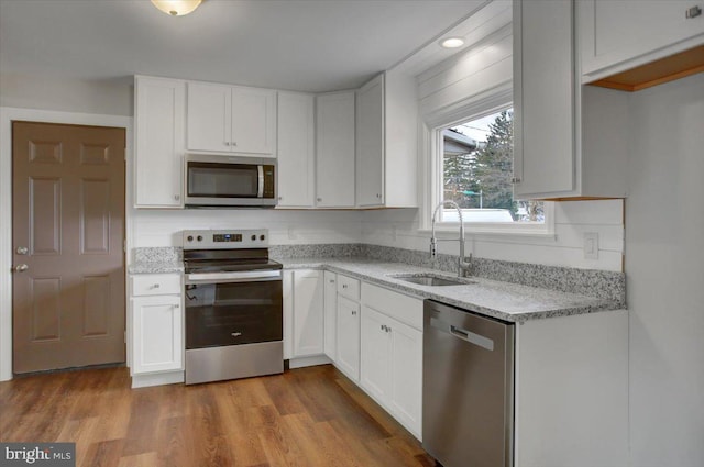 kitchen featuring stainless steel appliances, white cabinetry, light hardwood / wood-style floors, and sink