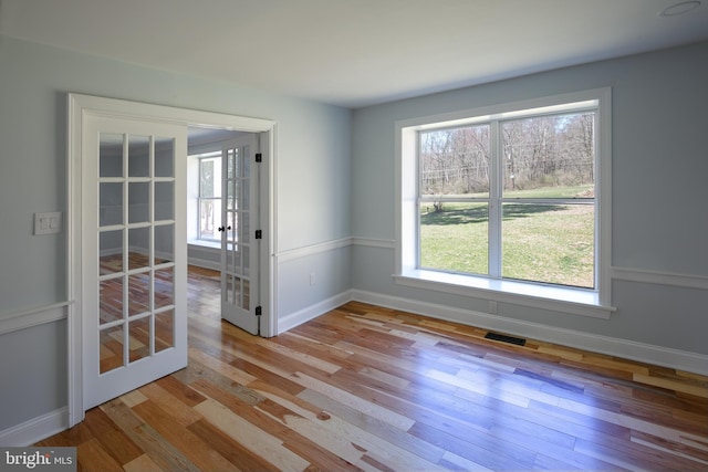 empty room with french doors and light hardwood / wood-style flooring