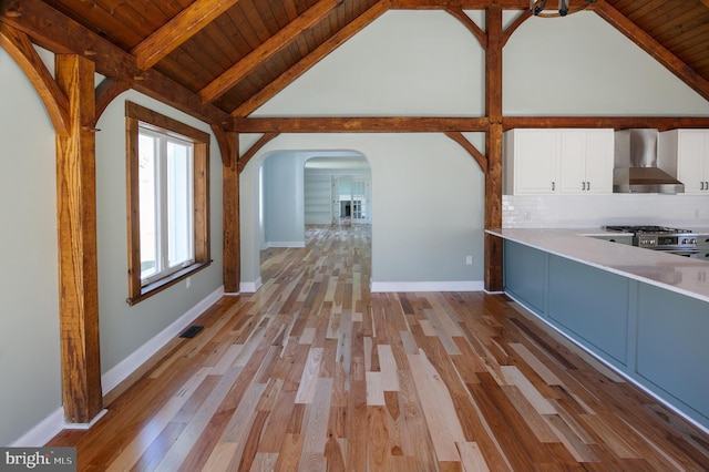 unfurnished living room featuring beamed ceiling, light wood-type flooring, high vaulted ceiling, and wooden ceiling