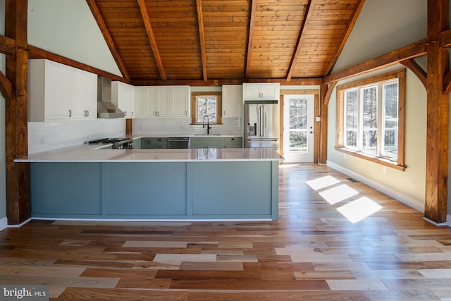 kitchen with sink, wall chimney range hood, light hardwood / wood-style floors, white cabinets, and appliances with stainless steel finishes