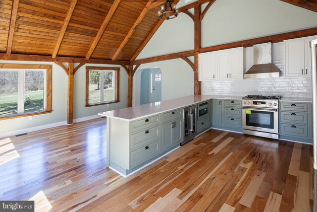 kitchen featuring stainless steel appliances, wall chimney range hood, light hardwood / wood-style flooring, kitchen peninsula, and gray cabinets