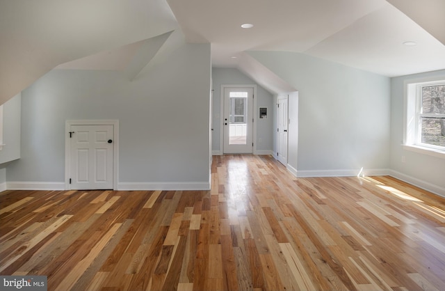 additional living space with light hardwood / wood-style floors and lofted ceiling