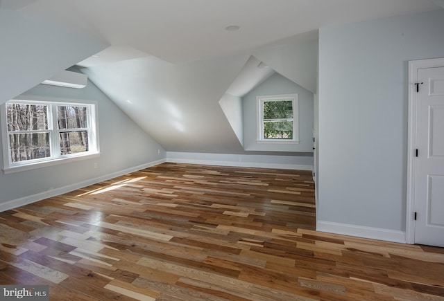 bonus room featuring plenty of natural light, dark wood-type flooring, and lofted ceiling