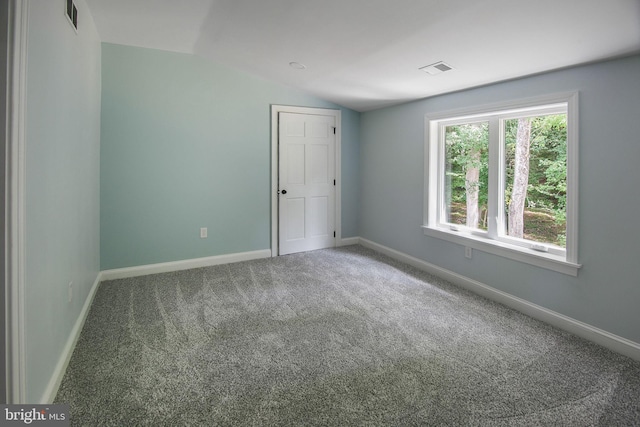 spare room featuring carpet flooring and lofted ceiling