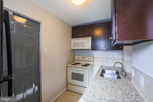 kitchen featuring sink, white appliances, light tile patterned floors, and light stone counters