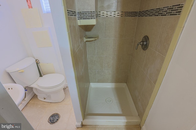 bathroom featuring tiled shower, toilet, and tile patterned flooring