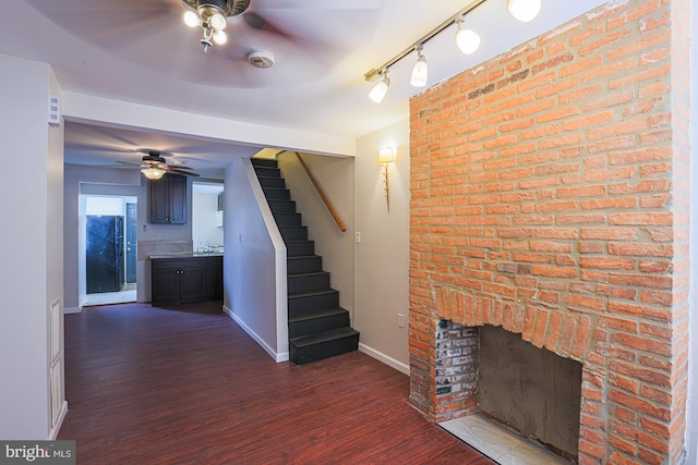 unfurnished living room with ceiling fan, dark hardwood / wood-style floors, and a brick fireplace