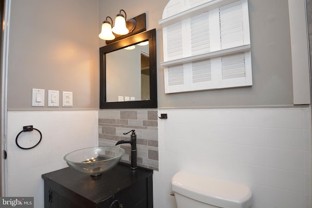 bathroom featuring vanity, toilet, and tile walls