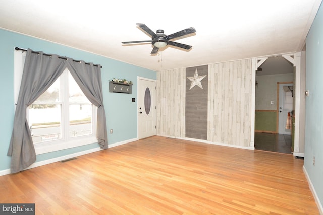 unfurnished room featuring wood walls, hardwood / wood-style floors, and ceiling fan