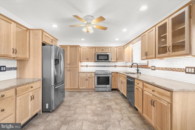 kitchen with light stone countertops, light brown cabinetry, stainless steel appliances, ceiling fan, and sink