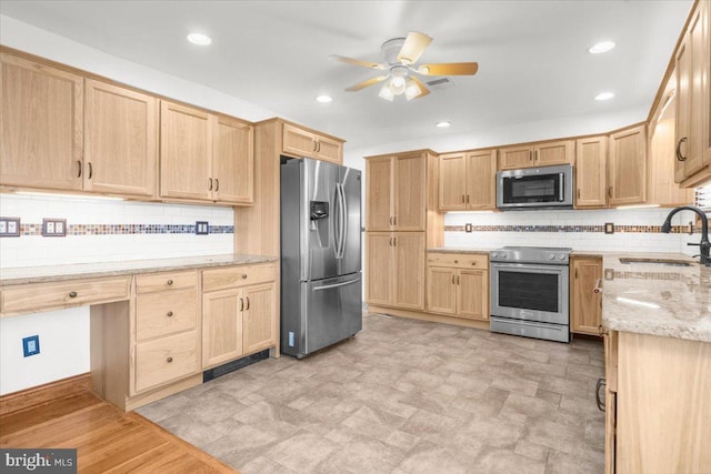 kitchen featuring light stone countertops, sink, ceiling fan, light brown cabinetry, and appliances with stainless steel finishes