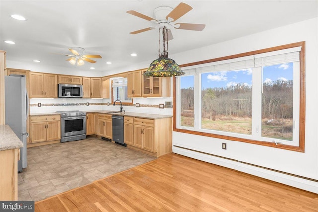 kitchen featuring a healthy amount of sunlight, stainless steel appliances, a baseboard radiator, pendant lighting, and decorative backsplash