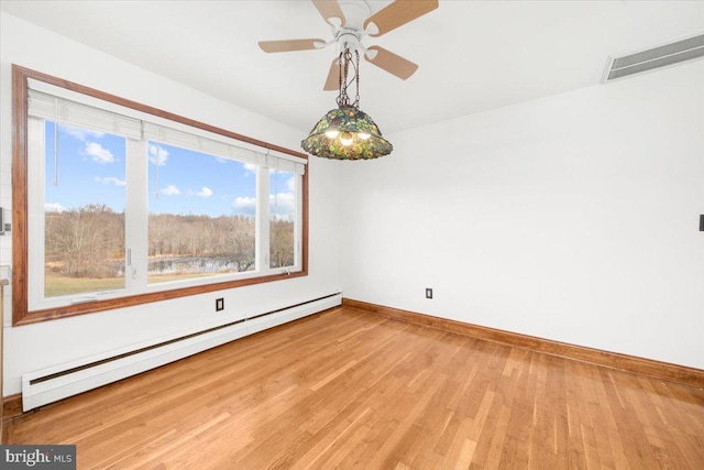 spare room with hardwood / wood-style flooring, ceiling fan, and a baseboard heating unit