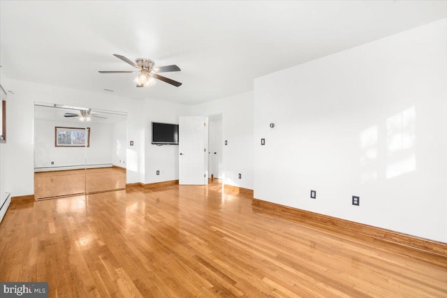 unfurnished living room with ceiling fan, wood-type flooring, and a baseboard heating unit