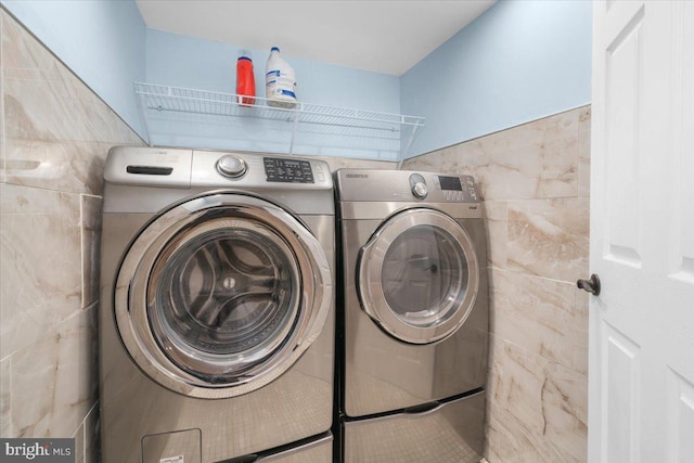 laundry area featuring tile walls and washing machine and clothes dryer