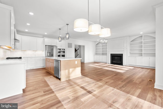 kitchen with stainless steel appliances, light hardwood / wood-style flooring, an island with sink, pendant lighting, and white cabinets