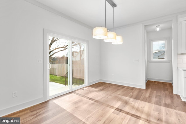 unfurnished dining area with light hardwood / wood-style floors, crown molding, and a wealth of natural light