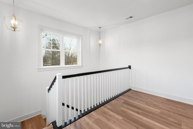 stairway featuring hardwood / wood-style floors and an inviting chandelier